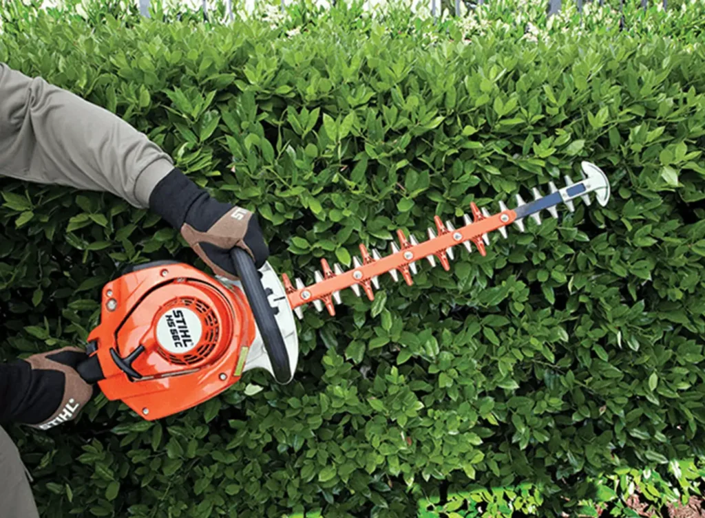 Element Turf & Outdoor Solutions - Employee trimming a hedge in Alton, IL.